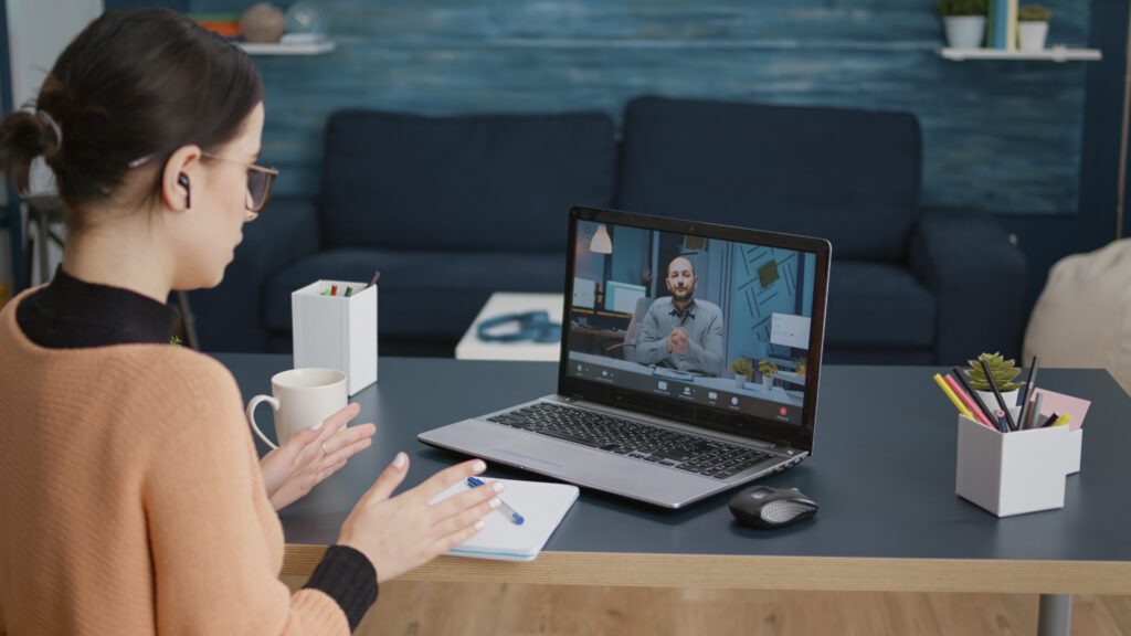 Mujer joven en videollamada con profesor, discutiendo clases online y aprendizaje a distancia.